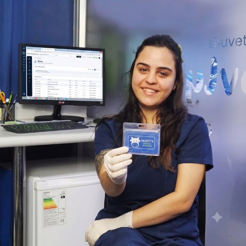 Una trabajadora de una clínica veterinaria muestra su credencial, con muvets abierto en el monitor.